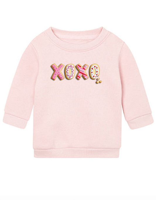 Schriftzug XOXO in Keksform mit Verzierungen in rosa und rot auf Baby Sweatshirt in Farbe rosa