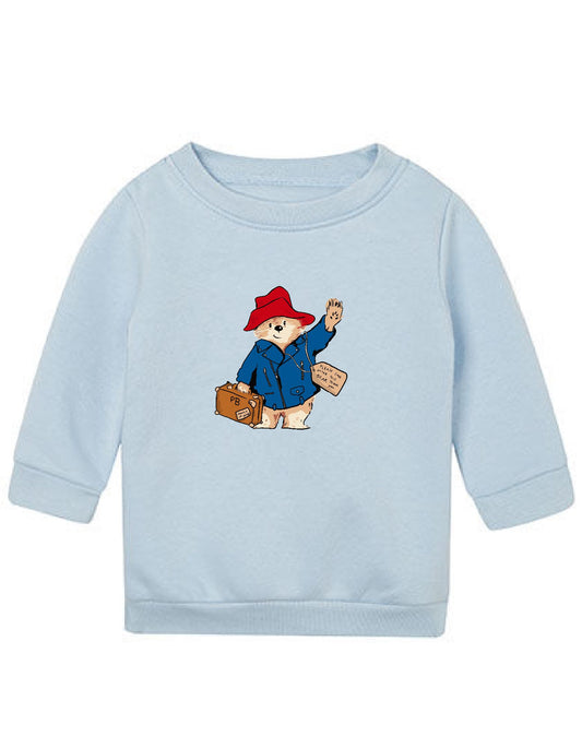 Zeichnung von Paddington mit rotem Hut, blauer Jacke. Er traegt einen Koffer & winkt. Aufgedruckt auf Baby Sweatshirt in Farbe hellblau