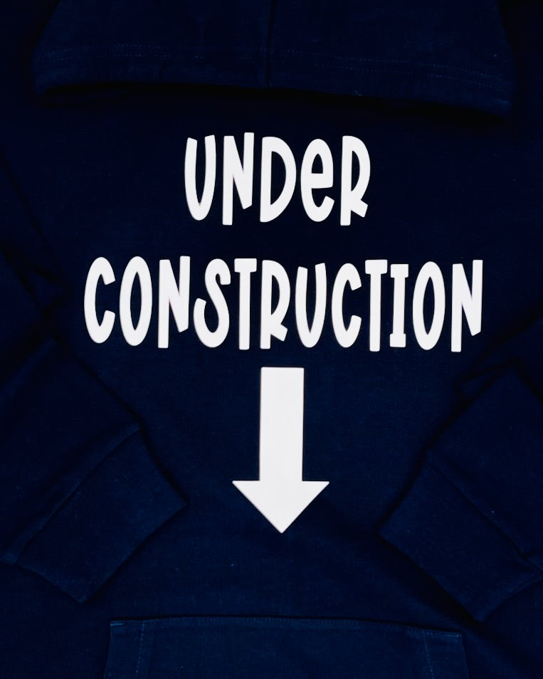 Schrift "UNDER CONSTRUCTION" untereinander und darunter abgebildet ein dicker Pfeil der nach unten zeigt. Alles ist in weiss.