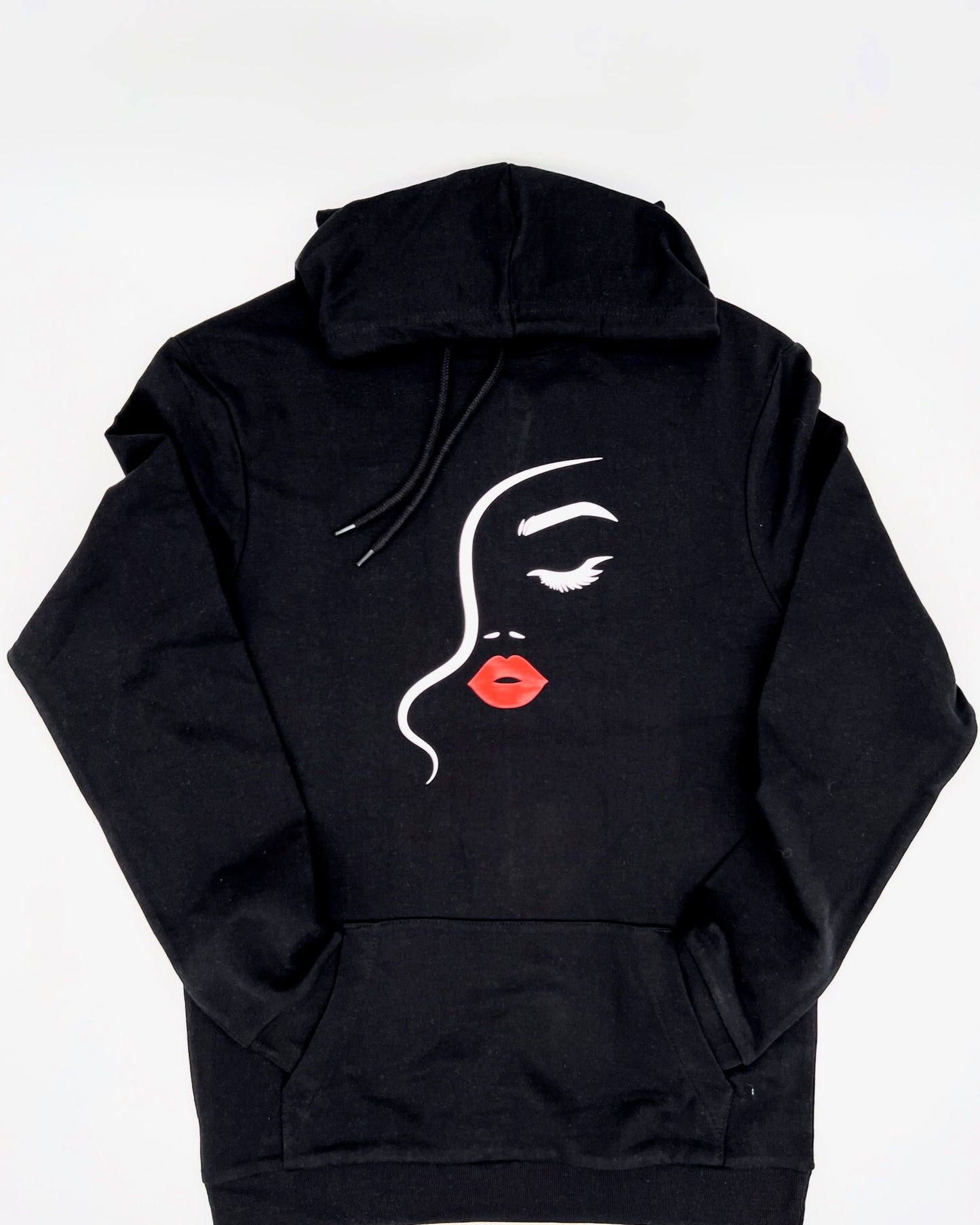 Hoodie in schwarz. Auf Brusthoehe ist ein Frauengesicht erkennbar abgebildet. Es besteht aus einem Haaransatz dargestellt durch eine geschwungene in Staerke variierende Linie in weiss. Das andeutete Auge mit Braue ist rechts davon in weiss. Von der Nase sind nur die Nasenloecher in weiss angedeutet. Darunter ist Mund und die Lippen sind in einem schoenen rot.