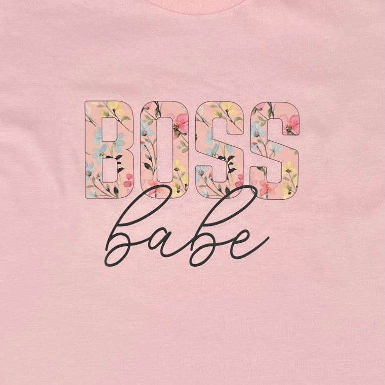 Detailansicht des Aufdruck "BOSS babe". Das Wort "BOSS" ist in Blockschrift und die einzelnen Buchstaben sind mit Blumen und Blueten in gelb, hellblau und rosa abgebildet. Das Wort "babe" steht darunter kursiv in schwarz geschrieben.