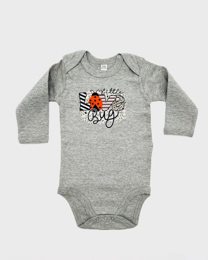 Schriftzug Little Love Bug auf der Brust. Die Buchstaben des Wortes LOVE sind mit einem Muster, das "O" ein Junikäfer in rot.