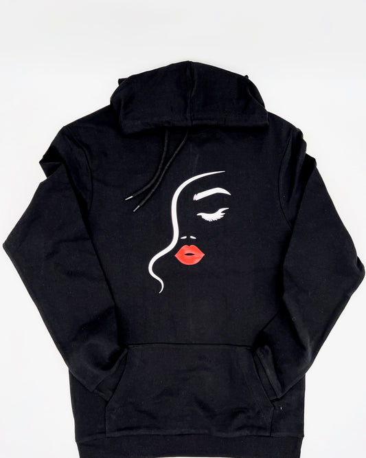 Hoodie in schwarz. Auf Brusthoehe ist ein Frauengesicht erkennbar abgebildet. Es besteht aus einem Haaransatz dargestellt durch eine geschwungene in Staerke variierende Linie in weiss. Das andeutete Auge mit Braue ist rechts davon in weiss. Von der Nase sind nur die Nasenloecher in weiss angedeutet. Darunter ist Mund und die Lippen sind in einem schoenen rot.